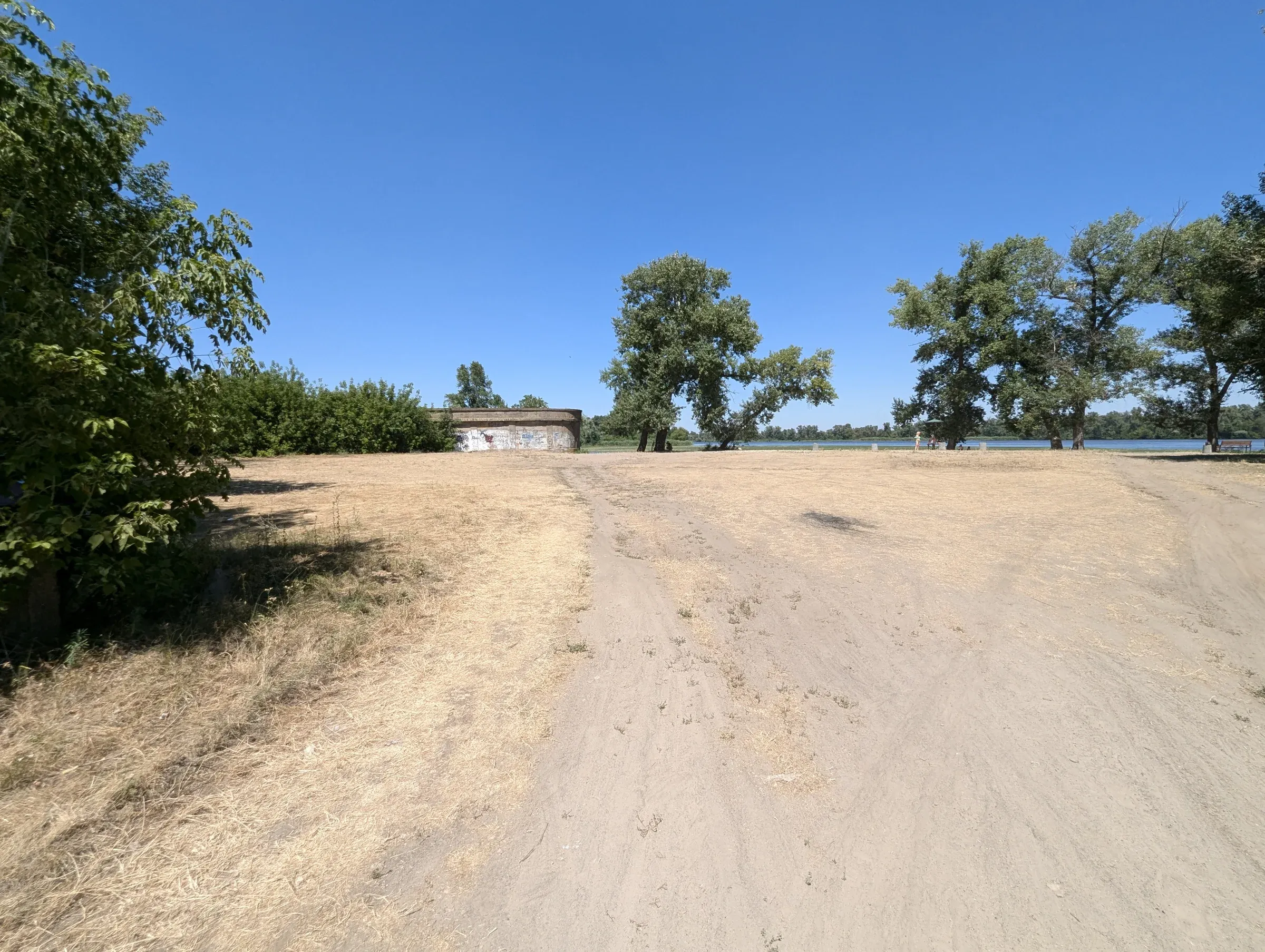 Широка піщана дорога до дерев біля води в Карнаухівці
